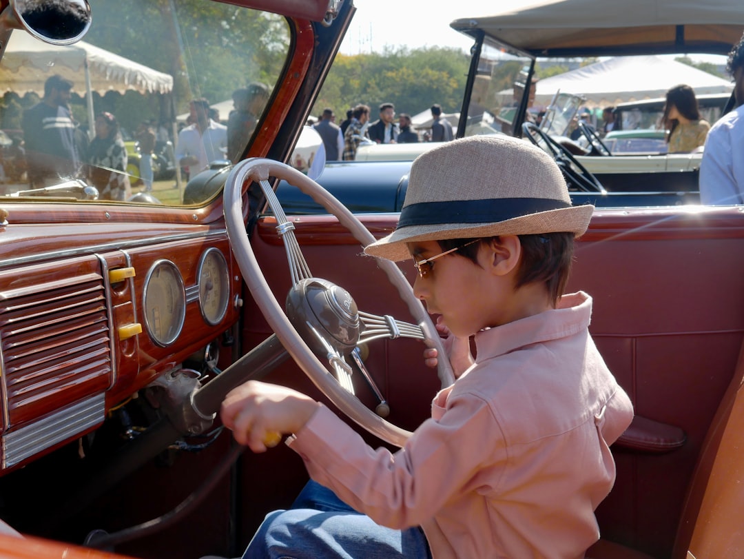 Young boy wearing hat sits in vintage car