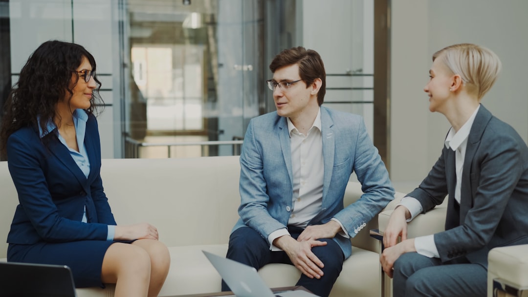 Three business people talking on a sofa.
